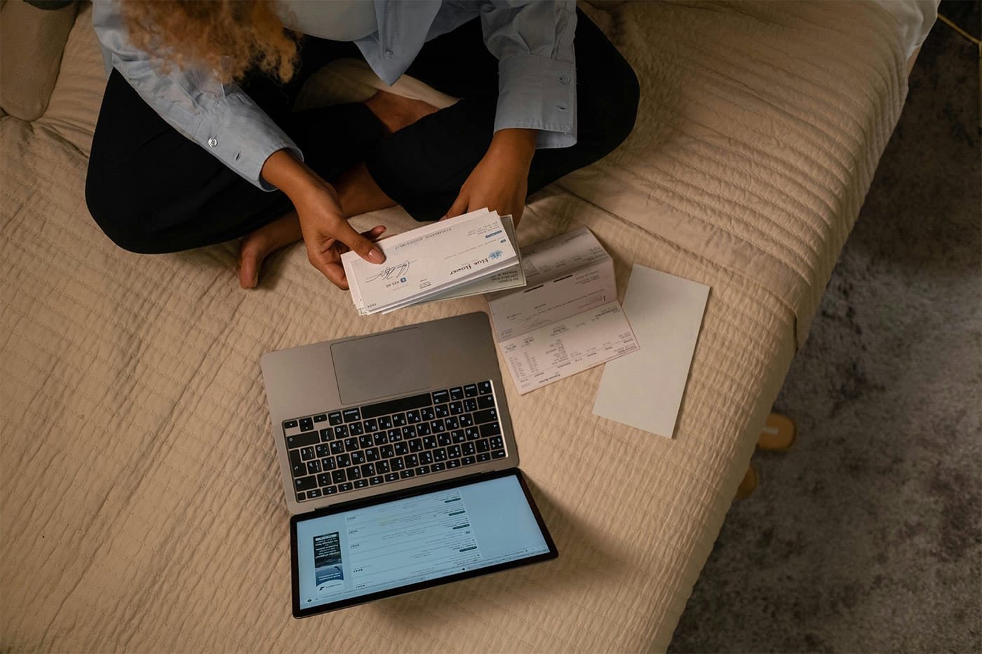 A person looking at cheques and paperwork with their laptop