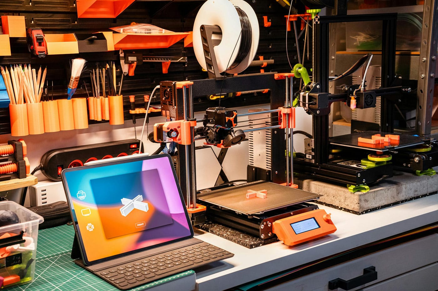 A workshop with a 3D printer and laptop showing a 3D printer design
